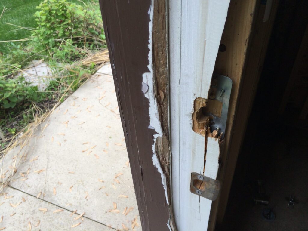 Door frame with visible damage and splintering near the lock area, suggesting forced entry.